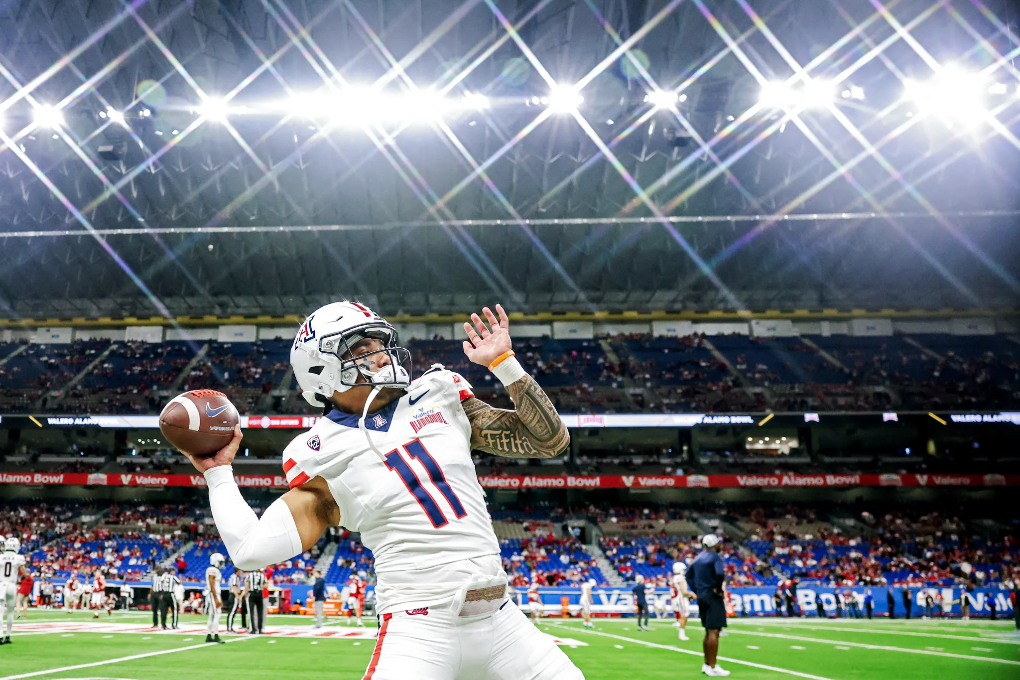 A football player passes the ball in a well lit stadium