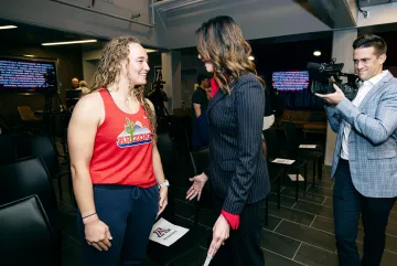A photograph of a student athlete smiling and speaking with the athletics director
